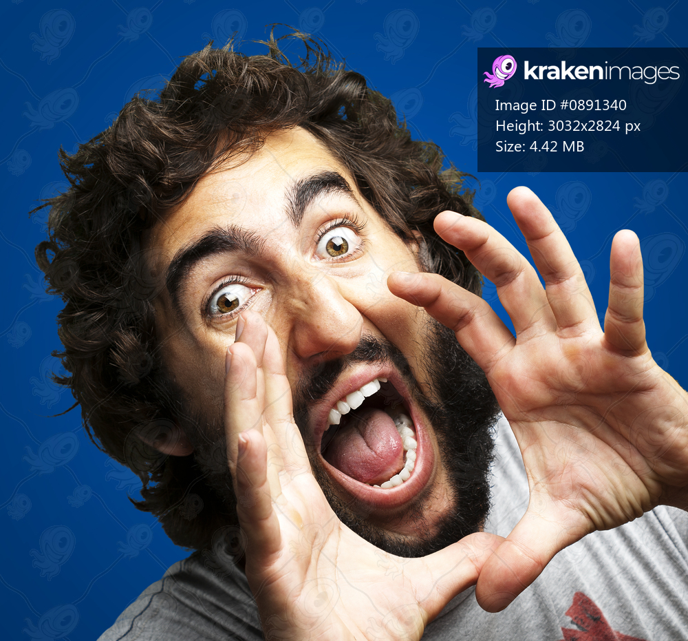 portrait of young man screaming against a blue background