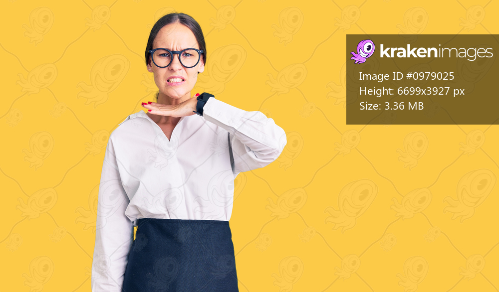 Beautiful brunette young woman wearing professional waitress apron cutting throat with hand as knife, threaten aggression with furious violence 