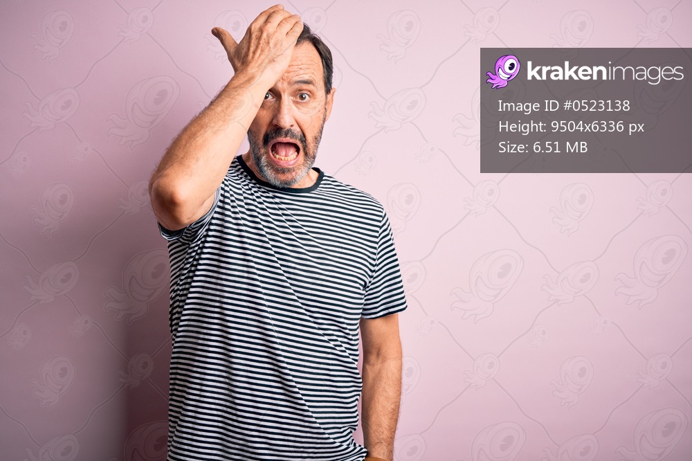 Middle age hoary man wearing casual striped t-shirt standing over isolated pink background surprised with hand on head for mistake, remember error. Forgot, bad memory concept.