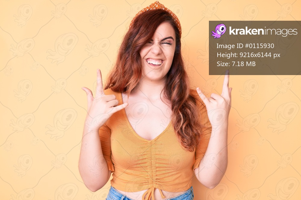 Young beautiful woman wearing casual clothes shouting with crazy expression doing rock symbol with hands up. music star. heavy concept. 