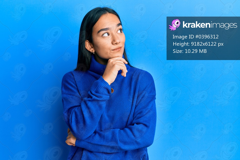 Young asian woman wearing casual winter sweater with hand on chin thinking about question, pensive expression. smiling with thoughtful face. doubt concept. 