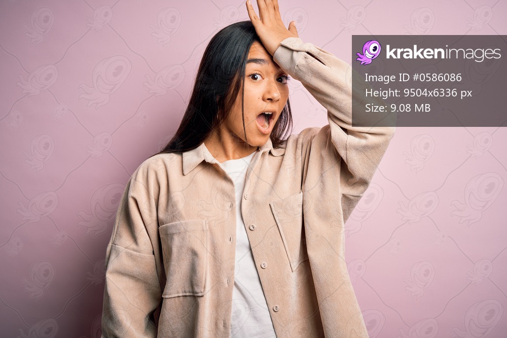 Young beautiful asian woman wearing casual shirt standing over pink background surprised with hand on head for mistake, remember error. Forgot, bad memory concept.