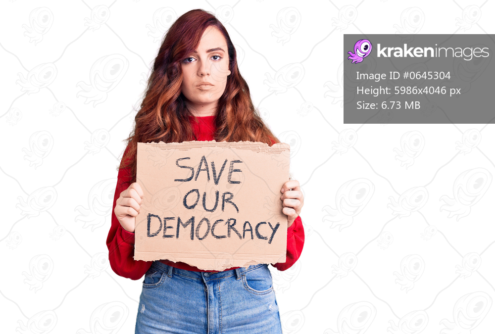 Young beautiful woman holding save our democracy protest banner thinking attitude and sober expression looking self confident 