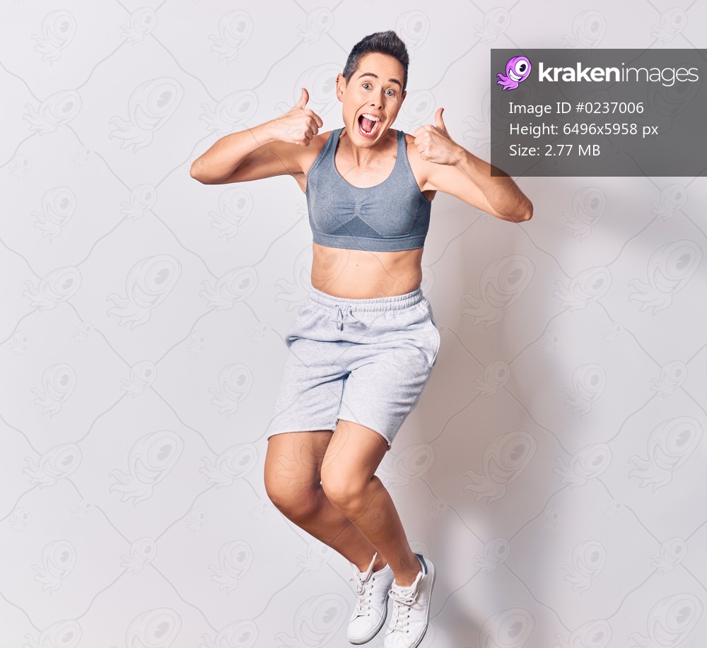 Young beautiful caucasian sportswoman wearing sportswear smiling happy. Jumping with smile on face over isolated white background