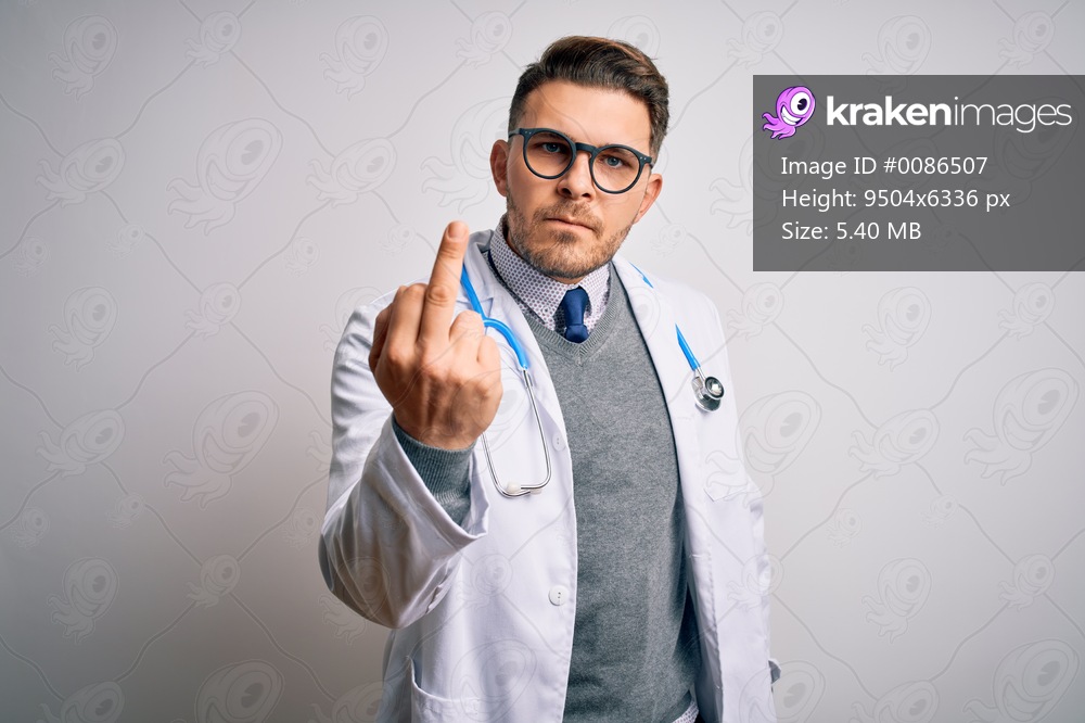 Young doctor man with blue eyes wearing medical coat and stethoscope over isolated background Showing middle finger, impolite and rude fuck off expression