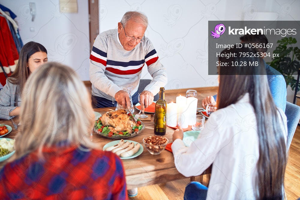 Beautiful group of people meeting smiling happy and confident. Carving roasted turkey celebrating Thanksgiving Day at home