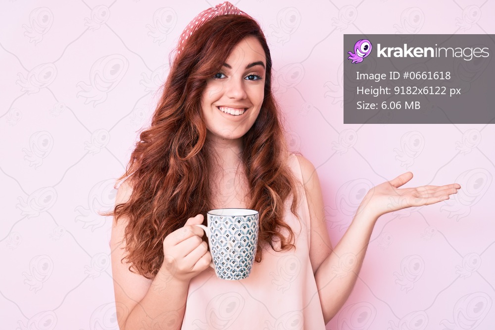 Young beautiful woman holding coffee celebrating achievement with happy smile and winner expression with raised hand 