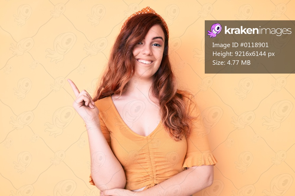 Young beautiful woman wearing casual clothes with a big smile on face, pointing with hand and finger to the side looking at the camera. 