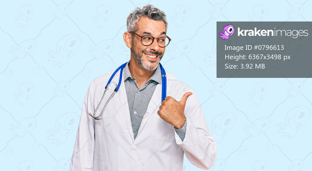 Middle age grey-haired man wearing doctor uniform and stethoscope smiling with happy face looking and pointing to the side with thumb up. 