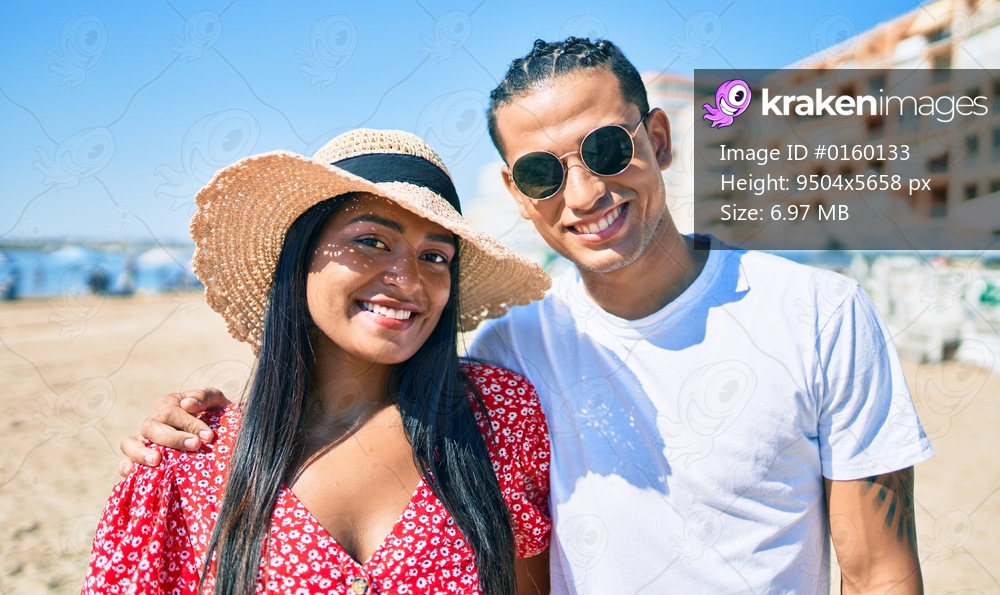 Young latin couple smiling happy and hugging at the beach.