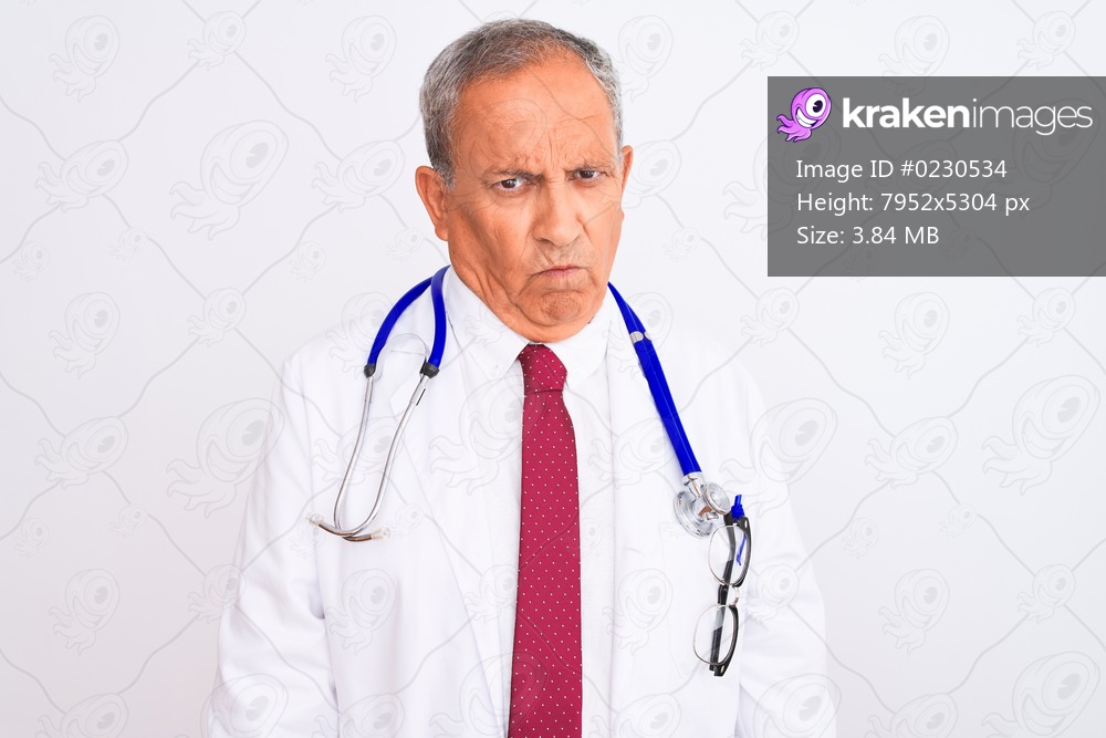 Senior grey-haired doctor man wearing stethoscope standing over isolated white background skeptic and nervous, frowning upset because of problem. Negative person.
