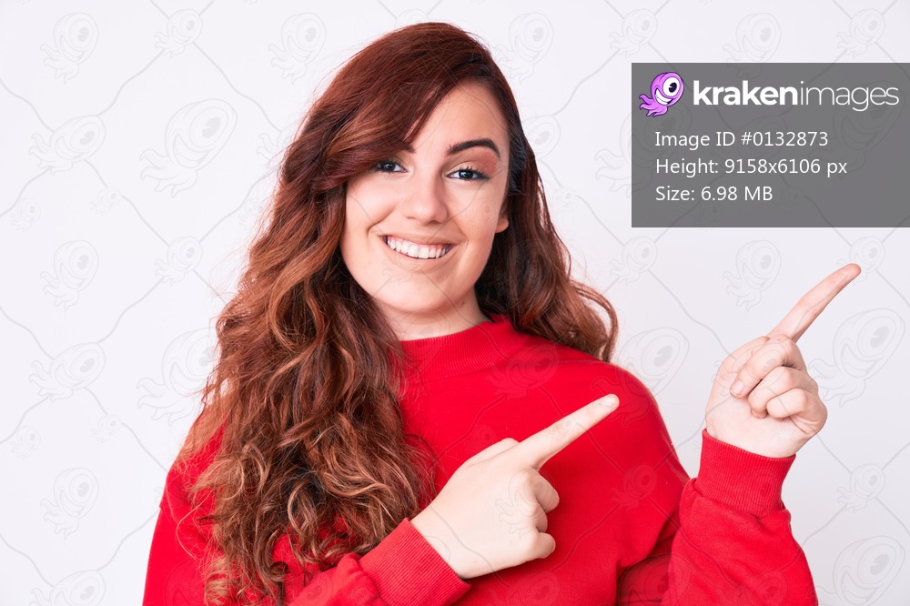 Young beautiful woman wearing casual clothes smiling and looking at the camera pointing with two hands and fingers to the side. 