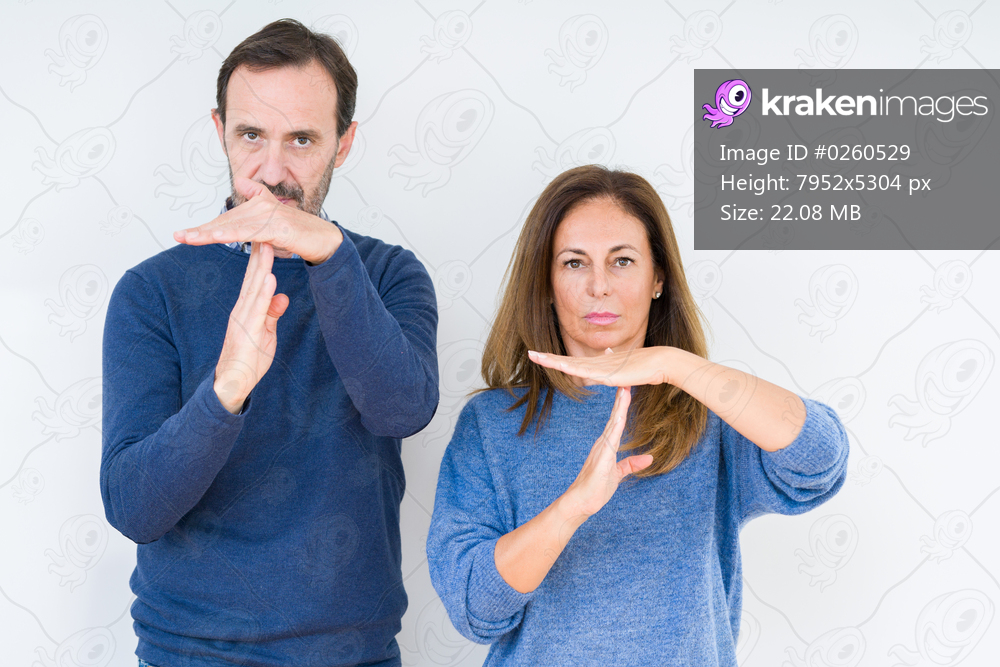 Beautiful middle age couple in love over isolated background Doing time out gesture with hands, frustrated and serious face