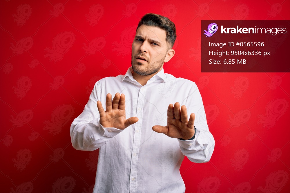 Young business man with blue eyes wearing elegant shirt standing over red isolated background Moving away hands palms showing refusal and denial with afraid and disgusting expression. Stop and forbidden.