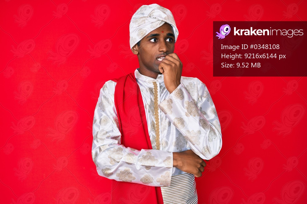 Handsome indian man wearing tradition sherwani saree clothes looking stressed and nervous with hands on mouth biting nails. anxiety problem. 