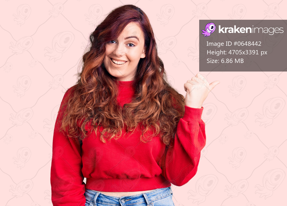 Young beautiful woman wearing casual winter sweater smiling with happy face looking and pointing to the side with thumb up. 