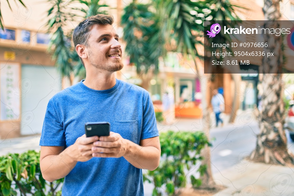 Young caucasian man smiling happy using smartphone at the city.