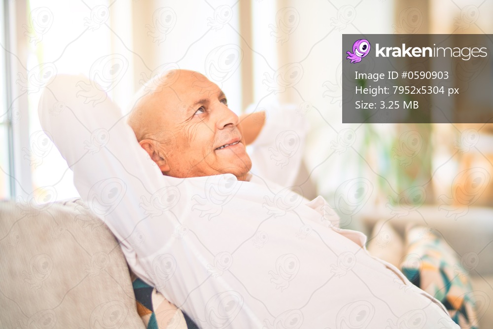 Senior handsome man smiling happy and confident. Sitting on the sofa relaxed at home