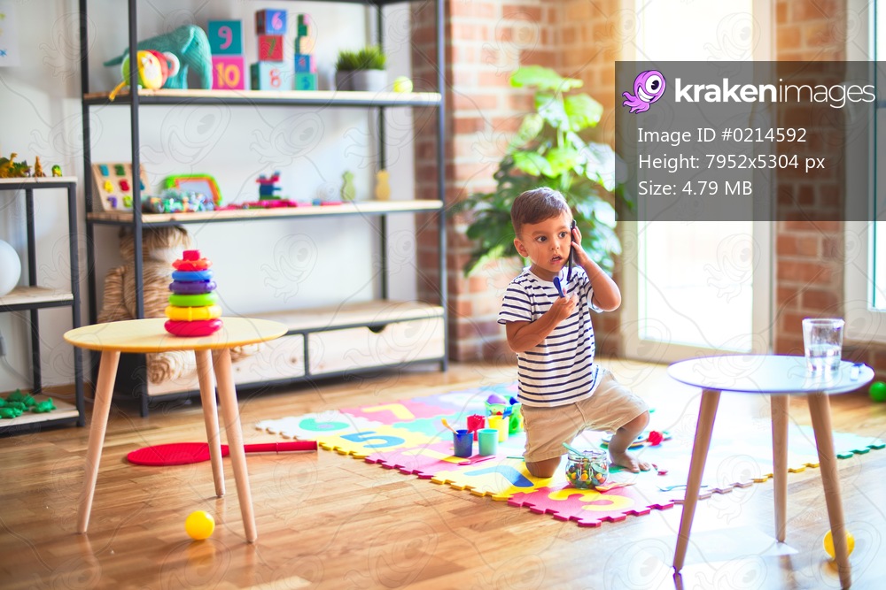 Beautiful toddler boy talking on the smartphone at kindergarten