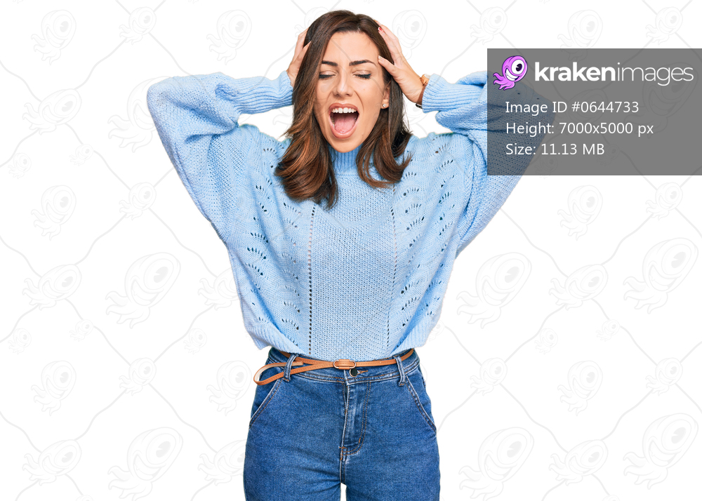 Young brunette woman wearing casual winter sweater crazy and scared with hands on head, afraid and surprised of shock with open mouth 