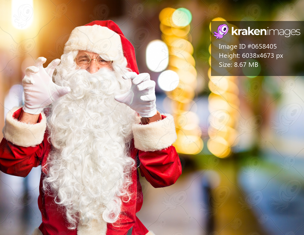 Middle age handsome man wearing Santa Claus costume and beard standing smiling funny doing claw gesture as cat, aggressive and sexy expression