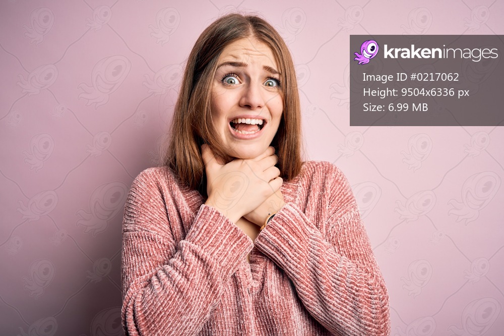 Young beautiful redhead woman wearing casual sweater over isolated pink background shouting and suffocate because painful strangle. Health problem. Asphyxiate and suicide concept.