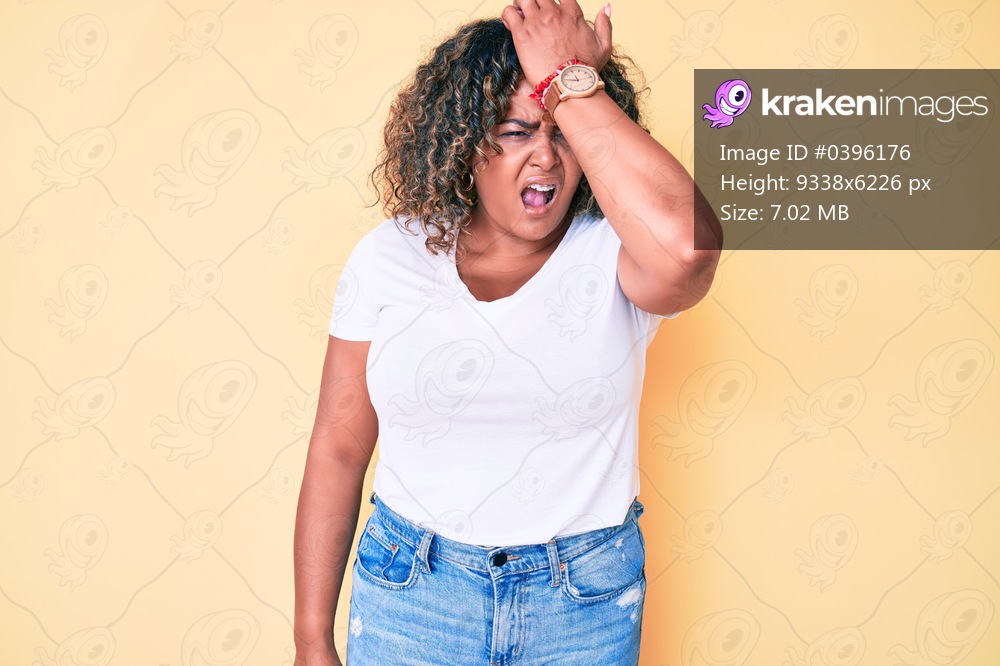 Young african american plus size woman wearing casual white tshirt surprised with hand on head for mistake, remember error. forgot, bad memory concept. 