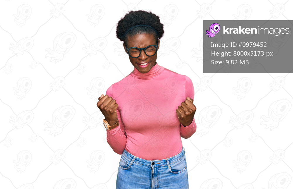 Young african american girl wearing casual clothes and glasses very happy and excited doing winner gesture with arms raised, smiling and screaming for success. celebration concept. 
