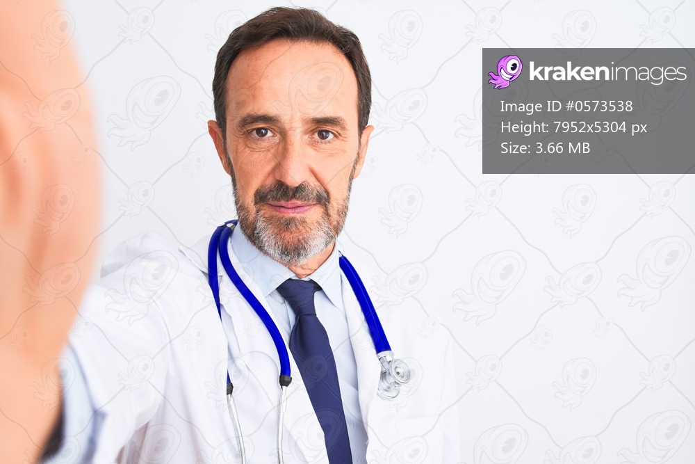 Middle age doctor man wearing stethoscope make selfie over isolated white background with a confident expression on smart face thinking serious