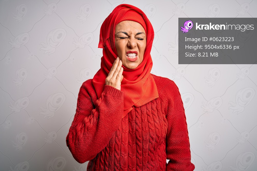 Middle age brunette woman wearing muslim traditional hijab over isolated white background touching mouth with hand with painful expression because of toothache or dental illness on teeth. Dentist