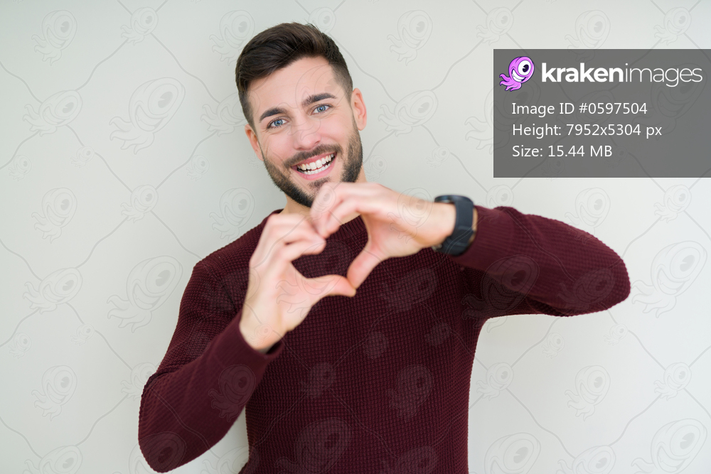 Young handsome man wearing a sweater over isolated background smiling in love showing heart symbol and shape with hands. Romantic concept.