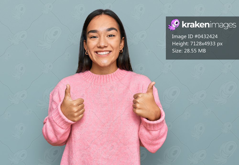 Young asian woman wearing casual winter sweater success sign doing positive gesture with hand, thumbs up smiling and happy. cheerful expression and winner gesture. 