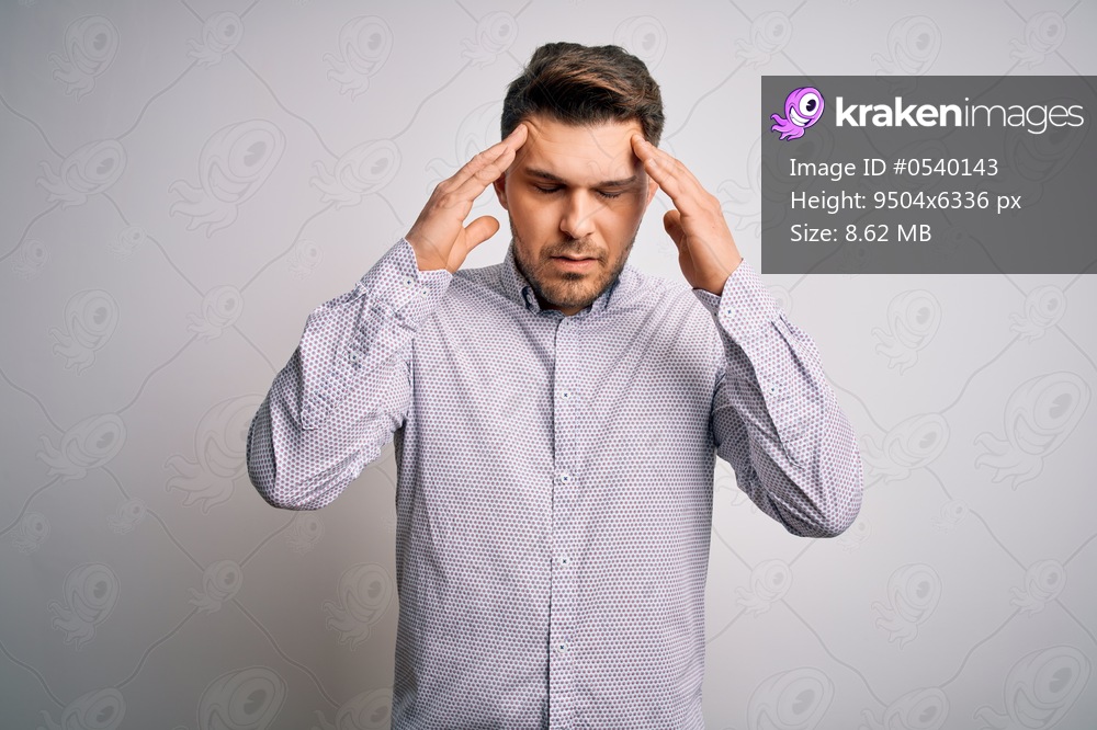 Young business man with blue eyes standing over isolated background with hand on head for pain in head because stress. Suffering migraine.