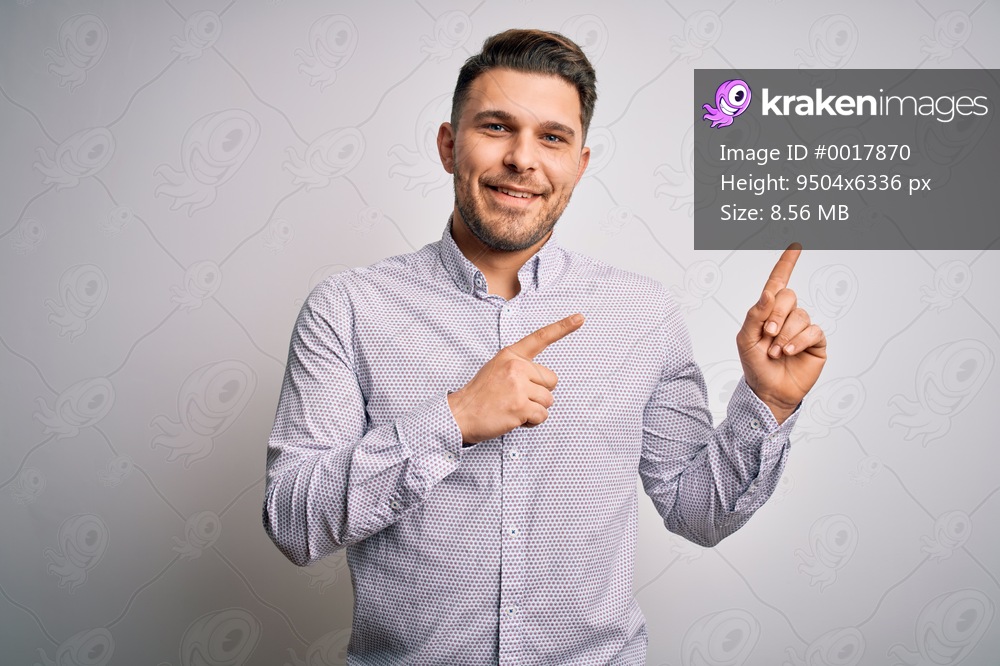 Young business man with blue eyes standing over isolated background smiling and looking at the camera pointing with two hands and fingers to the side.