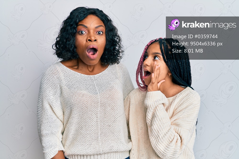 Beautiful african american mother and daughter wearing casual clothes and hugging hand on mouth telling secret rumor, whispering malicious talk conversation 