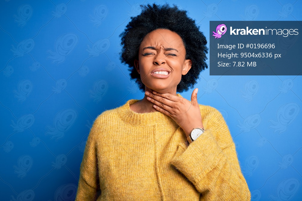 Young beautiful African American afro woman with curly hair wearing yellow casual sweater Touching painful neck, sore throat for flu, clod and infection