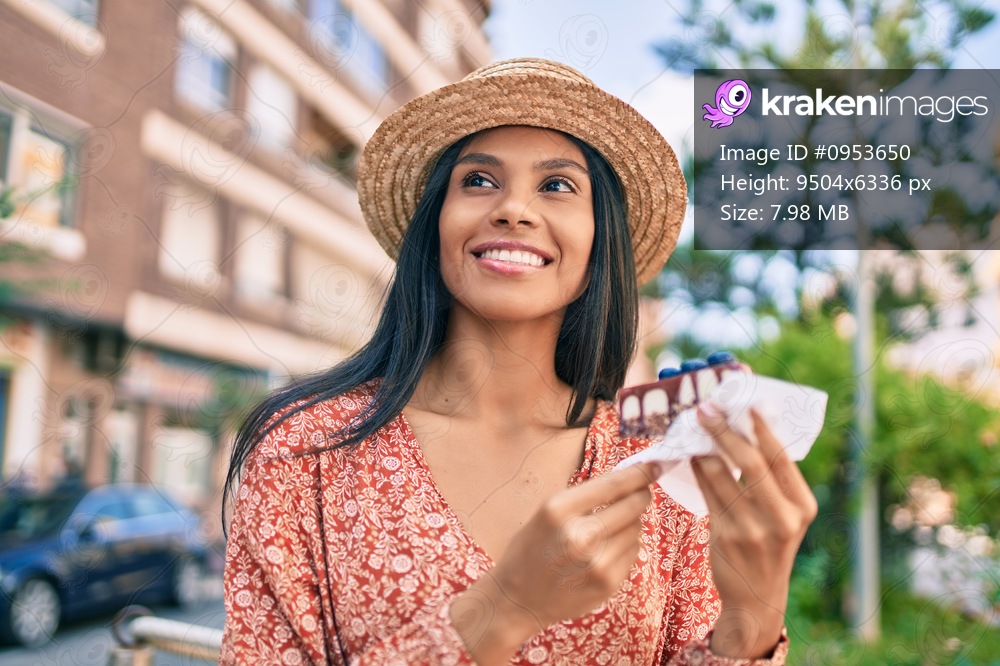 Young african american tourist woman on vacation eating cake at the city.