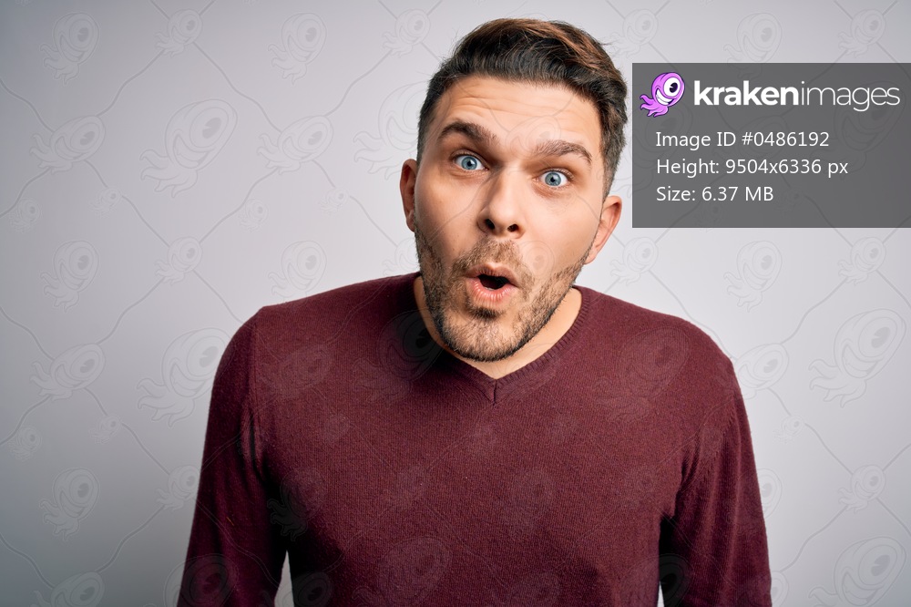 Young man with blue eyes wearing casual sweater standing over isolated background afraid and shocked with surprise expression, fear and excited face.