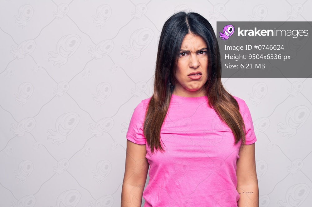 Young beautiful brunette woman wearing casual pink t-shirt standing over white background skeptic and nervous, frowning upset because of problem. Negative person.