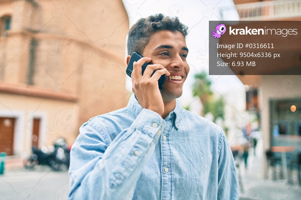 Young latin man smiling happy talking on the smartphone walking at the city.