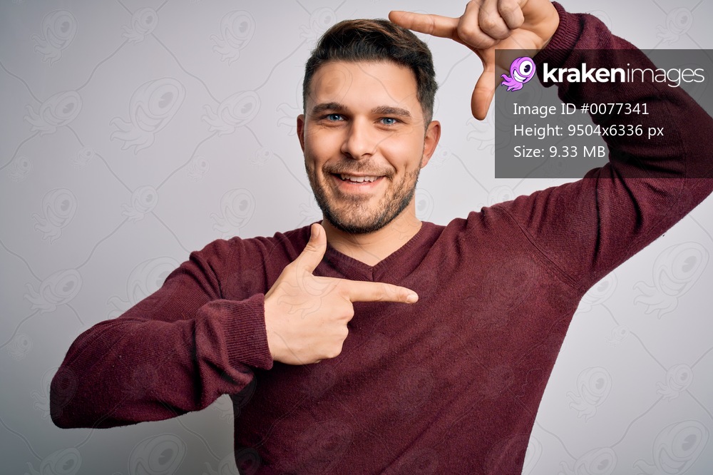 Young man with blue eyes wearing casual sweater standing over isolated background smiling making frame with hands and fingers with happy face. Creativity and photography concept.