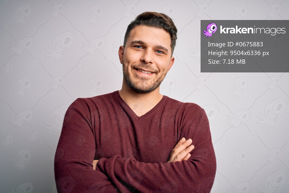 Young man with blue eyes wearing casual sweater standing over isolated background happy face smiling with crossed arms looking at the camera. Positive person.