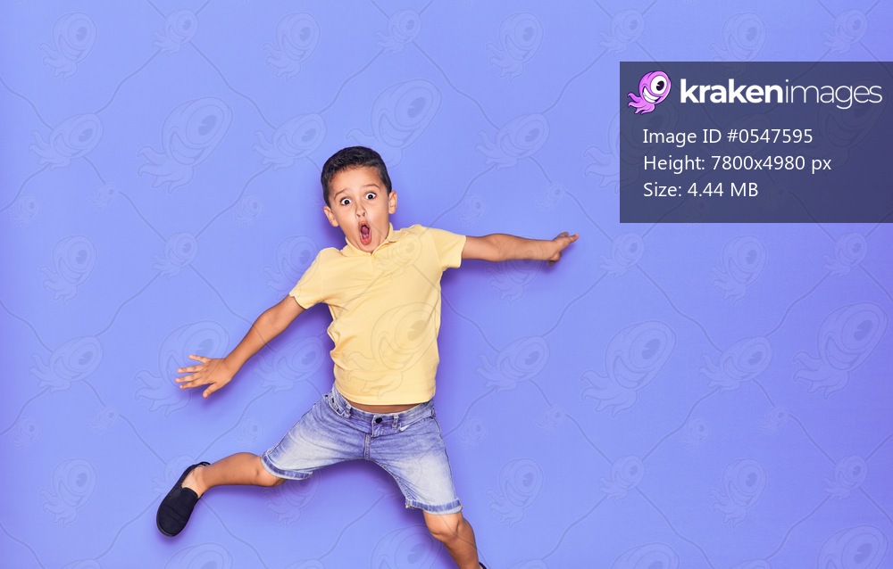 Adorable kid wearing casual clothes jumping over isolated purple background