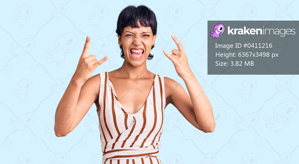 Young brunette woman with short hair wearing summer outfit shouting with crazy expression doing rock symbol with hands up. music star. heavy concept. 