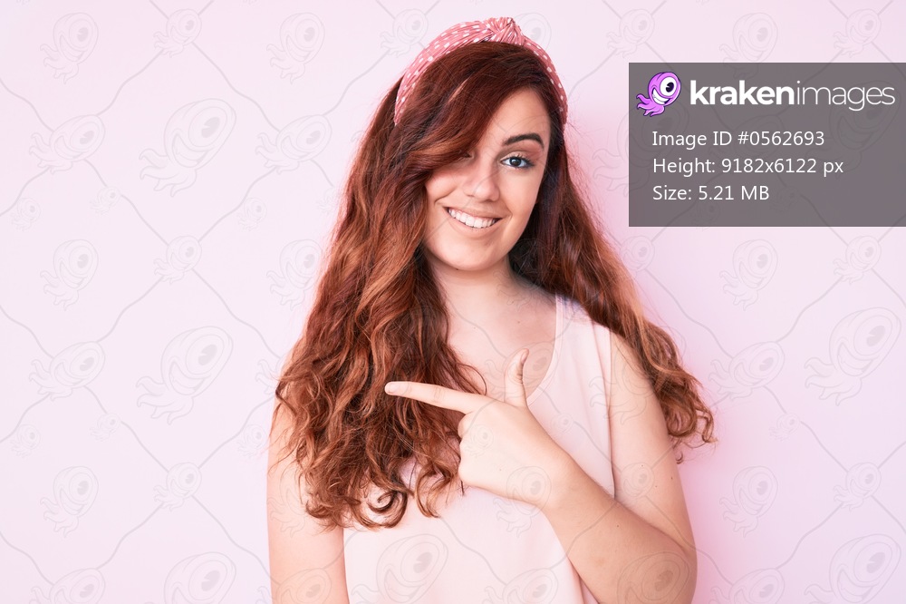 Young beautiful woman wearing casual clothes cheerful with a smile on face pointing with hand and finger up to the side with happy and natural expression 