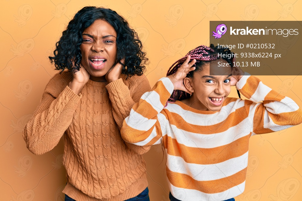 Beautiful african american mother and daughter wearing wool winter sweater trying to hear both hands on ear gesture, curious for gossip. hearing problem, deaf 