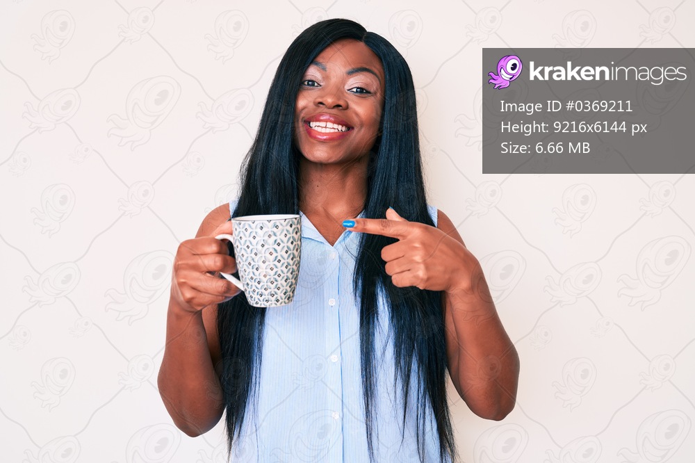 Young african american woman holding coffee smiling happy pointing with hand and finger 