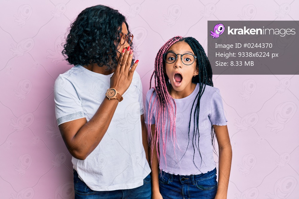 Beautiful african american mother and daughter wearing casual clothes and glasses hand on mouth telling secret rumor, whispering malicious talk conversation 