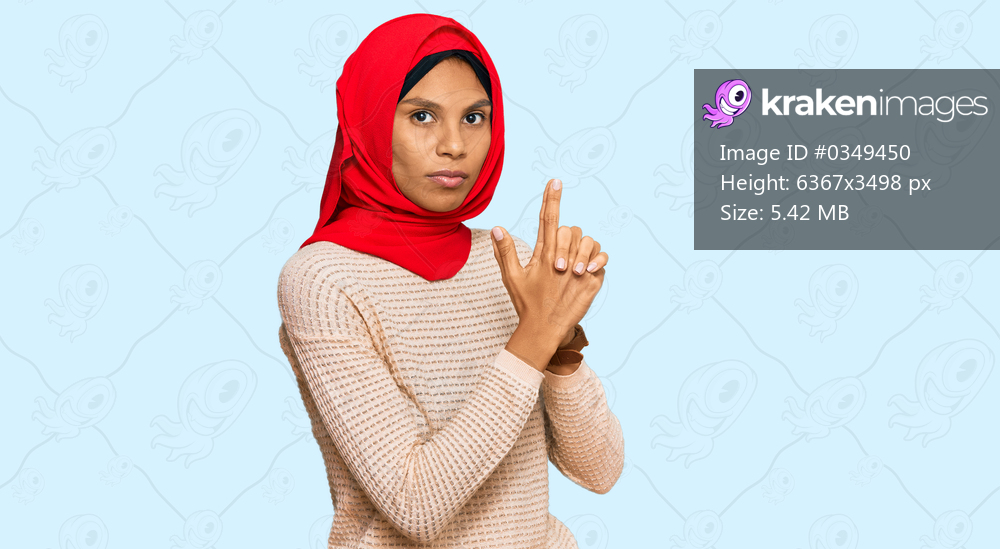 Young african american woman wearing traditional islamic hijab scarf holding symbolic gun with hand gesture, playing killing shooting weapons, angry face 