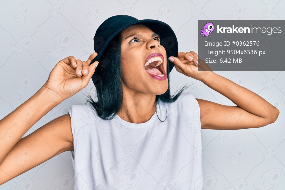 Young african american woman wearing fashion hat angry and mad screaming frustrated and furious, shouting with anger looking up. 